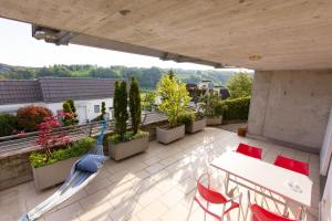 een patio met een tafel en stoelen op een balkon bij Hilltop-house, near train, 180° panorama, friendly in Birmensdorf