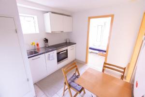 a kitchen with white cabinets and a wooden table at Hilltop-house, near train, 180° panorama, friendly in Birmensdorf
