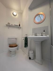 Baño blanco con aseo y lavamanos en Cockleshell Cottage en Falmouth