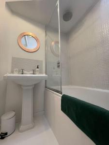 a white bathroom with a sink and a shower at Cockleshell Cottage in Falmouth