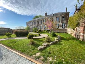 un antico edificio in pietra con un giardino di fronte di Relais Les Loges-Etretat a Les Loges