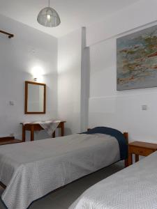a bedroom with two beds and a table and a mirror at Livadia Studios in Ropanianá