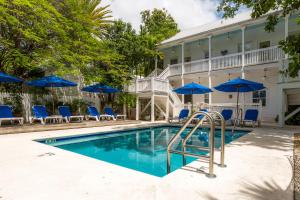 una piscina con sillas y sombrillas azules en Casa 325 Guesthouse, en Key West