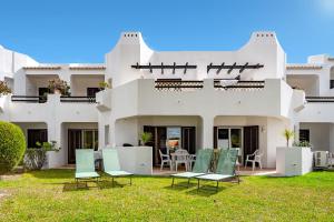 a white house with chairs and tables in the yard at Charming Balaia Golf Village Apartment - Sleeps 6 in Albufeira