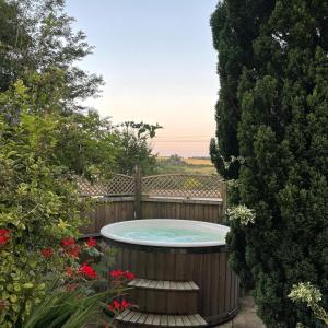 una bañera de hidromasaje en un jardín con árboles y flores en Gorgeous Country Cottage on outskirts of Bath with Wood Fired Hot Tub en Midford