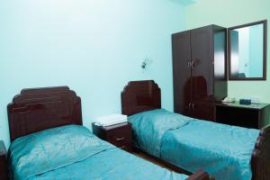 1 dormitorio con 2 camas y pared azul en Syuniq Hotel, en Goris