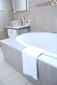 a white bath tub sitting in a bathroom at Open House Hotel in Mbabane