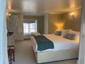 Un dormitorio con una gran cama blanca y una ventana en Gorgeous Country Cottage on outskirts of Bath with Wood Fired Hot Tub, en Midford