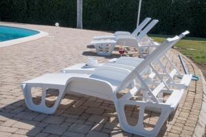 eine Reihe weißer Gartenstühle neben einem Pool in der Unterkunft Holiday-home-italy in Melissano