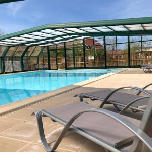 a swimming pool with a chair on a patio at Camping-Caravaning de la Mollière in Groffliers