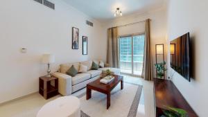 a living room with a white couch and a table at Hometown Apartments Trendy One Bed Apt in Ontario Tower in Dubai