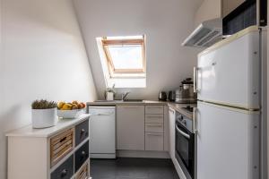uma pequena cozinha com electrodomésticos brancos e uma janela em Veeve - Footsteps from the Arc de Triomphe em Paris