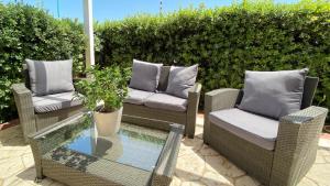 three wicker chairs and a glass table on a patio at Xenia Hotel in Villasimius