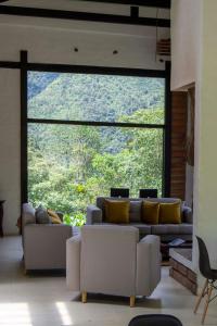 ein Wohnzimmer mit einem Sofa und einem großen Fenster in der Unterkunft Neblina Bird in Otavalo