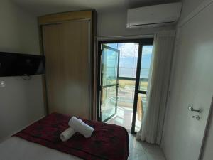 Schlafzimmer mit einem Bett und einem Fenster mit Meerblick in der Unterkunft Arraso de apê na Praia de Camburi in Vitória