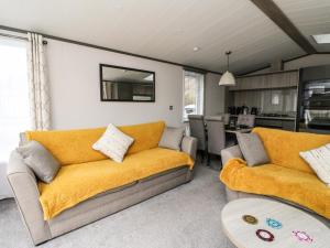 a living room with two couches and a kitchen at Red Kite Lodge in Crieff