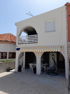 a white building with a balcony and a patio at Apartmani Pleša in Vir