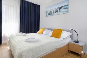 um quarto com uma cama com almofadas amarelas em Jantar Apartamenty - AQUARIUS Apartamenty em Kolobrzeg