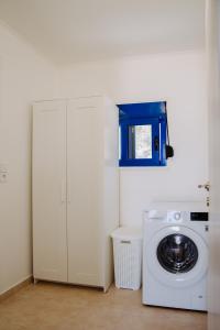 a laundry room with a washing machine and a blue window at Endless Horizon At Stegna in Archangelos