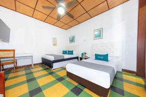 Zimmer mit 2 Betten, einem Schreibtisch und einem TV in der Unterkunft Ayenda Sarayu House in Medellín