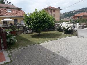 un jardín con un árbol y una valla blanca en La casa di Alice e Matteo, en Casarza Ligure