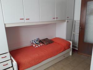 1 cama con manta naranja y armarios blancos en La casa di Alice e Matteo, en Casarza Ligure