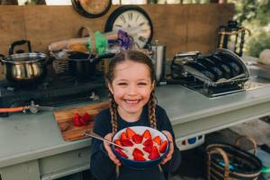 una niña sosteniendo un tazón de fresas en The Sleepy Explorer en Hallaton