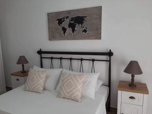 Un dormitorio con una cama con almohadas blancas y un mapa en la pared. en Alisachni, en Kini