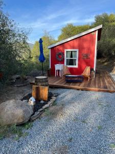 a red cabin with a table and chairs on a deck at McMillan Ranch Yosemite in Coarsegold