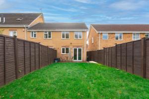 un patio trasero con una valla y césped verde en Cosy Contractor House & Garden & Free Parking en Swindon