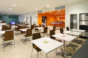 a restaurant with white tables and chairs and a cafeteria at One Oaxaca Centro in Oaxaca City