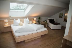 Schlafzimmer mit einem Bett mit weißer Bettwäsche und einem Fenster in der Unterkunft Schoiner See-Hotel, Garni in Gstadt am Chiemsee