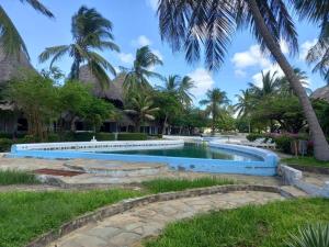 a swimming pool in front of a resort with palm trees at White Lion -the only one- in Malindi