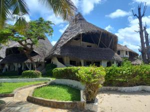 a house with a thatched roof on the beach at White Lion in Malindi