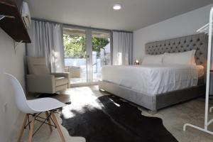 a bedroom with a large white bed and a chair at Viento Beach Lodge in Dorado