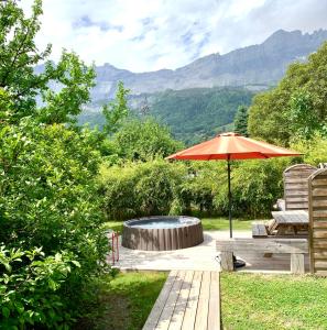 une terrasse avec un parasol, une table et des chaises dans l'établissement Appartement avec jacuzzi dans chalet privé, grande terrasse, parking gratuit, aux Houches