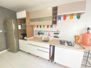 una cucina con armadi bianchi e frigorifero in acciaio inossidabile di Casa 181 Alto do Moura a Caruaru