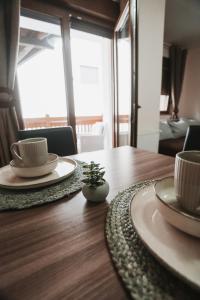 a wooden table with two plates and cups on it at Apartmani Zračak in Zlatibor