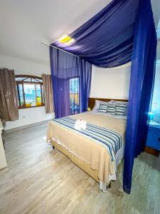 a bedroom with a bed with a blue canopy at Pousada Canto do Pescador in Bombinhas