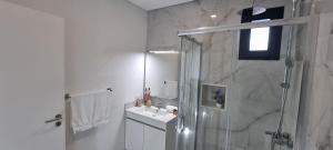 Un baño blanco con ducha y lavabo. en Villa Castanho I, en Calheta 7 fotos más