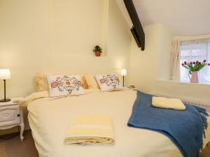 Cama blanca en habitación con ventana en Fox Hat Cottage, en Newton Abbot