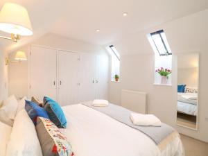 a bedroom with a large white bed with blue pillows at Fox Hat Cottage in Newton Abbot