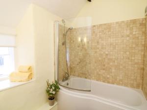 a bathroom with a shower and a bath tub at Fox Hat Cottage in Newton Abbot