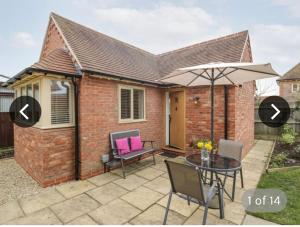 a brick house with a patio with a table and an umbrella at The Lodge in Eckington