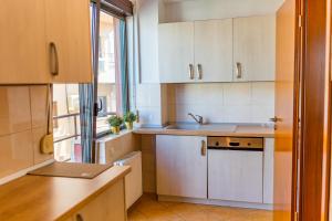 uma cozinha com armários brancos, um lavatório e uma janela em Sunny & spacious place with breathtaking view em Bucareste