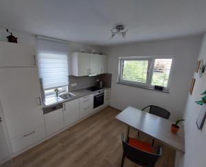 een keuken met witte kasten, een tafel en een wastafel bij Ferienwohnung Waldblick in Abenberg