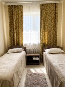 two beds in a room with a window and a rug at AL BARAKA in Borovoye