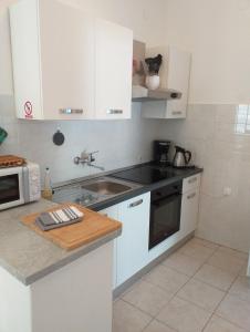 a kitchen with white cabinets and a sink at Apartments Jakov in Starigrad