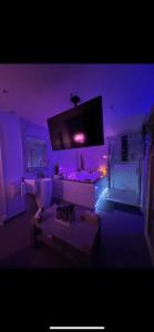 a living room with purple lighting and a tv at La Suite Etoilée in Domène