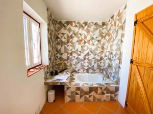 a bathroom with a tub with a tiled wall at Casa do Peladiço in Fataca +3 photos